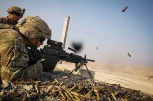 A U.S. soldier from the 3rd Cavalry Regiment is watched as he fires a squad automatic weapon during a training mission near forward operating base Gamberi, in the Laghman province of Afghanistan December 15, 2014. REUTERS/Lucas Jackson. 